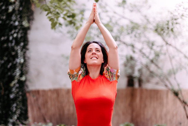 Yoga Lehrerin Joana in Yoga Pose mit über dem Kopf zusammengehaltenen Händen und erhobenem Blick